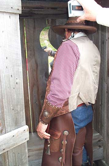 The Lazarus Man shooting pistol from the outhouse.