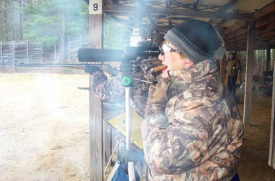 Long Suffering Wife keeping her husband's cigar going while he shoots.
